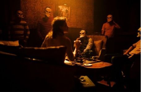 group of people drinking around a table wearing masks