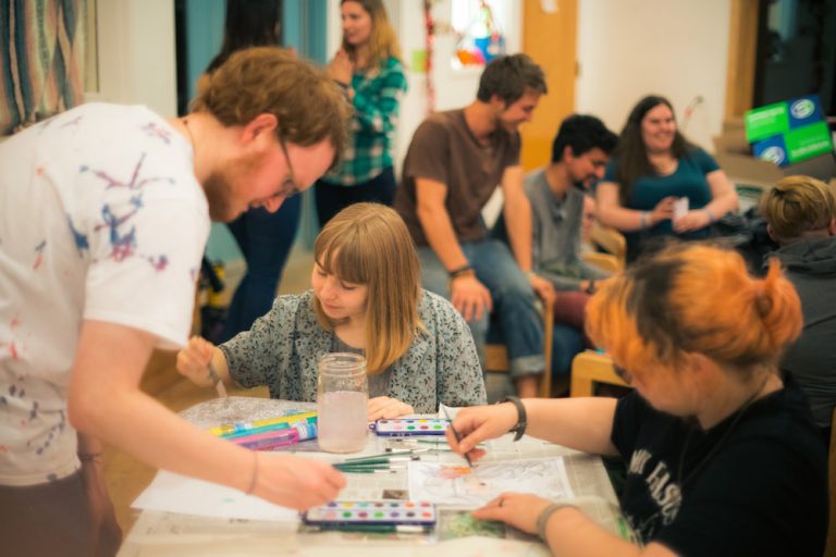 Professor helping students draw on paper