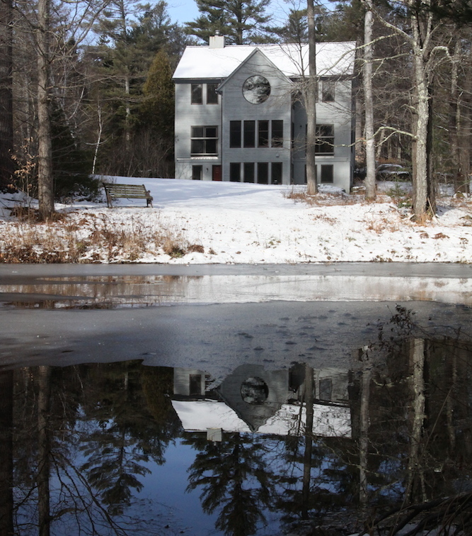 Beautiful white house covered in snow next to a lake