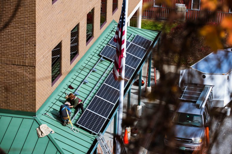 Workers installing brand new solar panels on a green roof