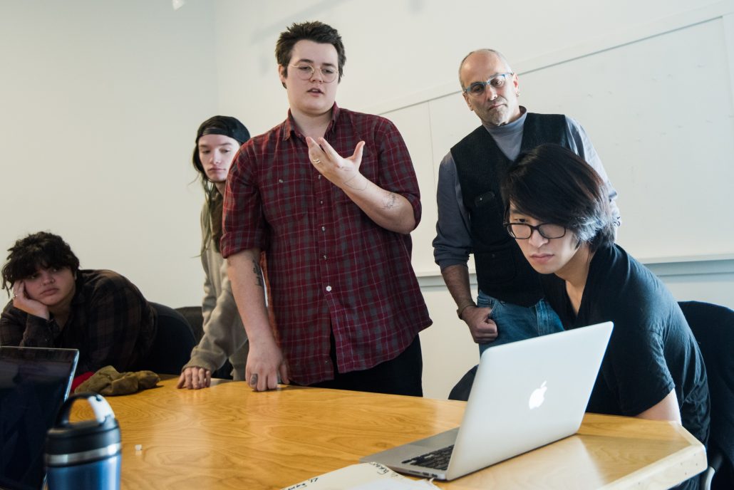 group of students looking at a laptop