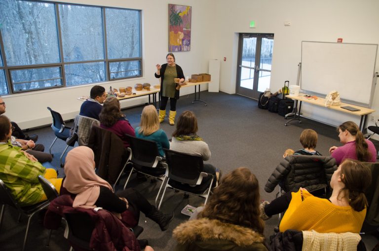 People sitting in a circle listening to a presenter speak