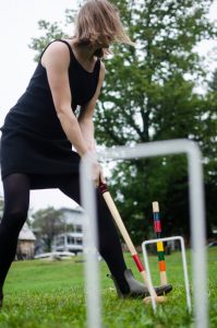A student laughing while playing croquet