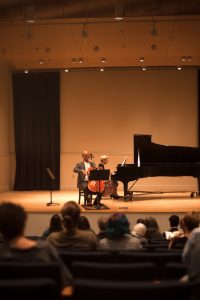 Two musicians playing the cello and piano on a grand stage