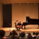 Two musicians playing the cello and piano on a grand stage