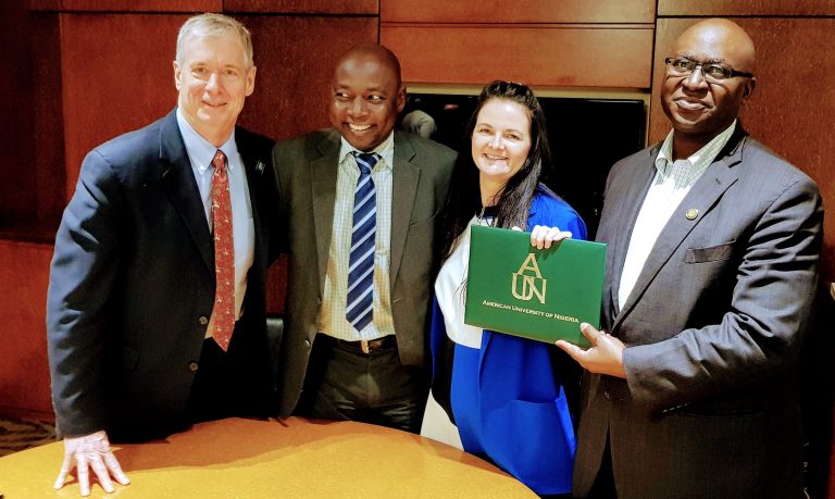 Four people posing with a certificate that reads "American University of Nigeria"