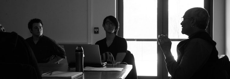 black and white photo of two students listening to a presenter speaking